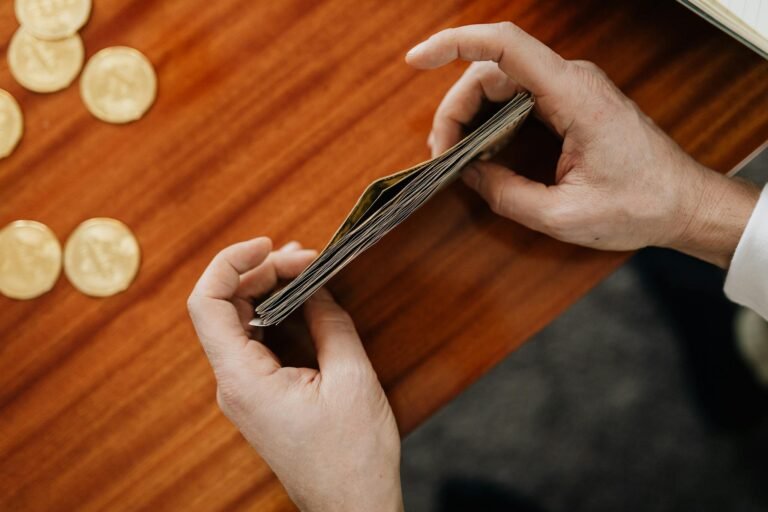 Close-up of hands counting currency with coins scattered on a wooden table. Perfect for finance and business themes.